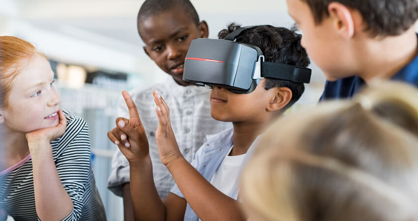 Mixed race child with vr virtual reality goggles in classroom. M